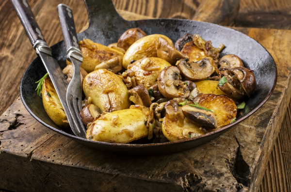 Bratkartoffel mit Pilzen in einer Eisenpfanne